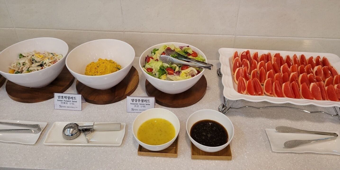Un buffet proposant divers plats, notamment une salade de potiron aux saveurs sucrées, des herbes aromatiques au goût prononcé et un assortiment de tranches d’agrumes.