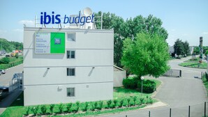 A modern building with a sign reading "ibis budget" and directional signs for "Sortie GARONOR" and "Prendre GARONOR". - ibis budget Aeroport le Bourget Garonor (Le Blanc-Mesnil)