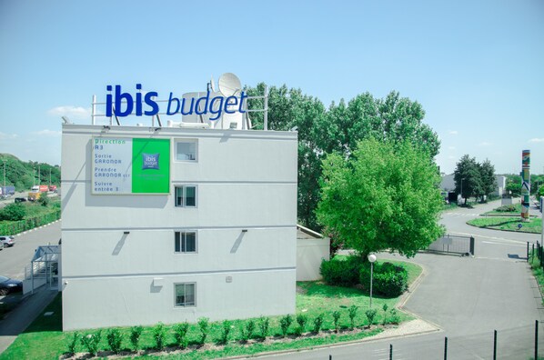 A modern building with a sign reading "ibis budget" and directional signs for "Sortie GARONOR" and "Prendre GARONOR". - ibis budget Aeroport le Bourget Garonor (Le Blanc-Mesnil)