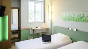 Habitación de hotel con dos camas, un escritorio, una computadora portátil, un ventanal y una pared verde.
