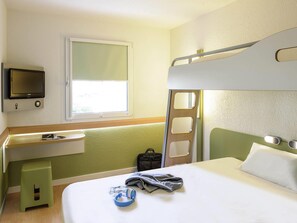 A hotel room with a bunk bed, a desk with a chair, a television mounted on the wall, and a window providing natural light. - ibis budget Aeroport le Bourget Garonor (Le Blanc-Mesnil)