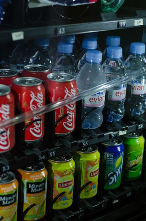 Una màquina expenedora amb diverses begudes, incloent Coca-Cola, aigua Evian, suc d'aranja Minute Maid, te fred Lipton, Sprite i altres refrescos.