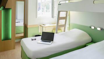 Ein Schlafraum mit Etagenbetten, ein Laptop auf der unteren Ebene, einem Schreibtisch und einem Fenster.