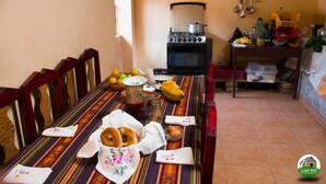 A dining area with a table set for four, a stove, and kitchen utensils. - Loma Wasi Village (Cotacachi)
