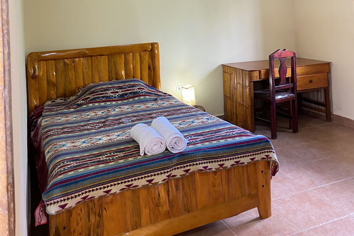 A bedroom with a wooden bed, a desk, and a chair.