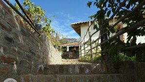 A stone staircase leading to a house with a tiled roof and a small garden area. - Loma Wasi Village (Cotacachi)