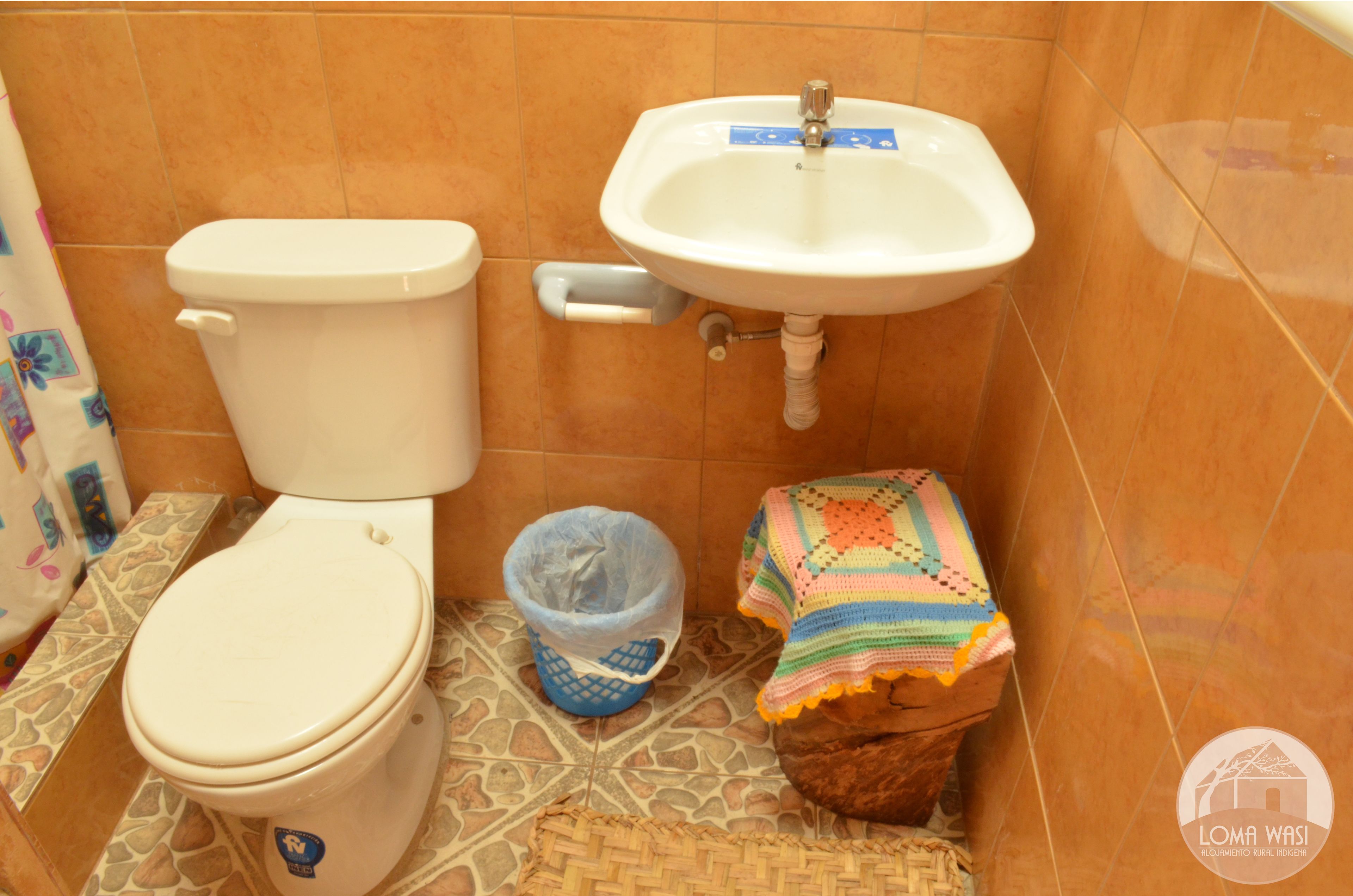 A bathroom with a toilet, sink, and a small trash bin.