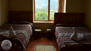 A room with two beds, a window with a view, and a woven mat on the floor. - Loma Wasi Village (Cotacachi)