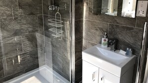 A modern bathroom with a glass shower enclosure, a white sink, and a mirror above it. - The Alba House (Edinburgh)