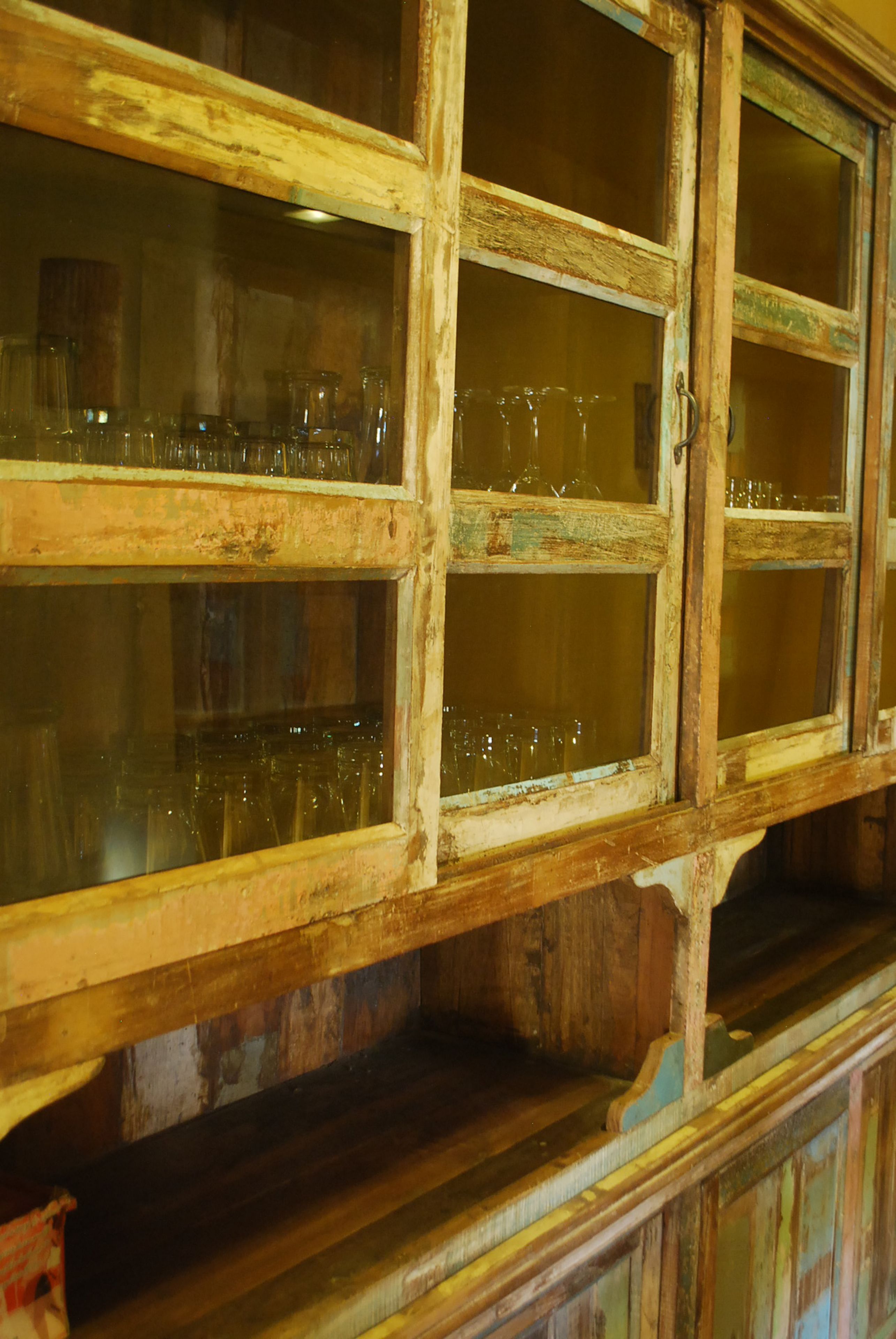 Eine Holzkabine mit mehreren Glastrennregalen, die leeres Glasgeschirr beherbergen.