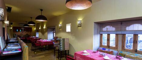 Un restaurante con varias mesas y cabinas, iluminación cálida y vistas al exterior a través de amplias ventanas.