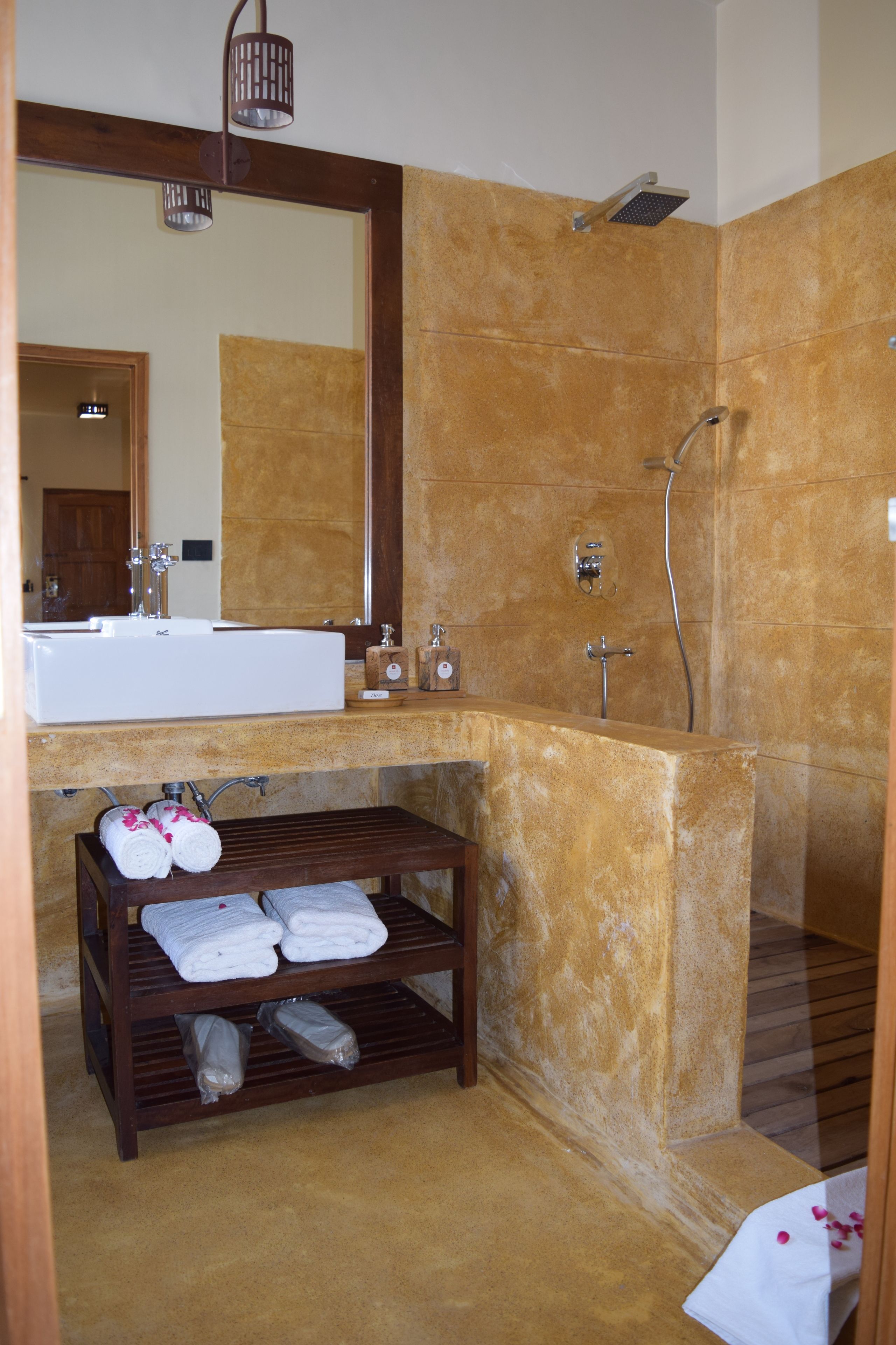 Une salle de bain avec un grand miroir, un lavabo, une douche et une étagère avec des serviettes.