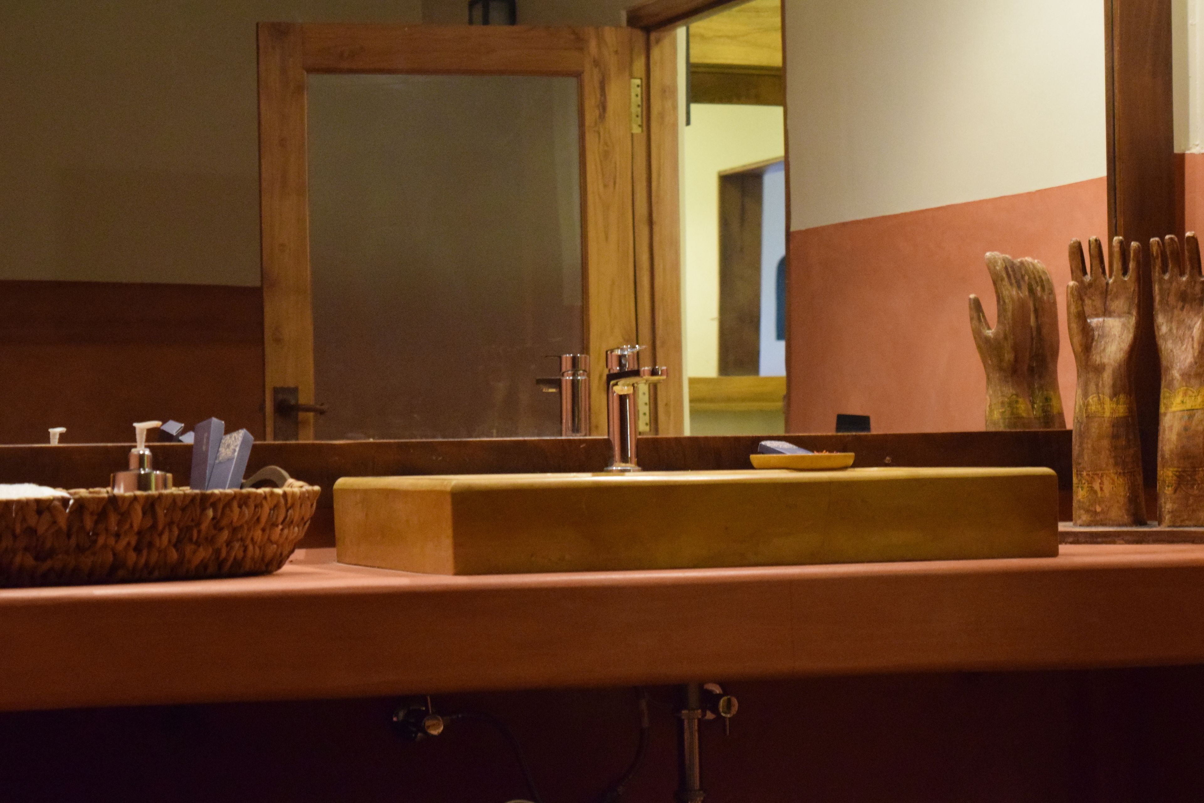 A bathroom with a wooden vanity, a sink with a soap dispenser, and a mirror.
