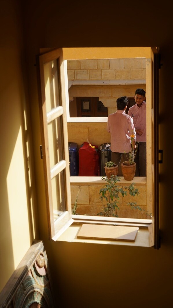 Une fenêtre ouverte, deux personnes à l’intérieur, une plante en pot et plusieurs valises.