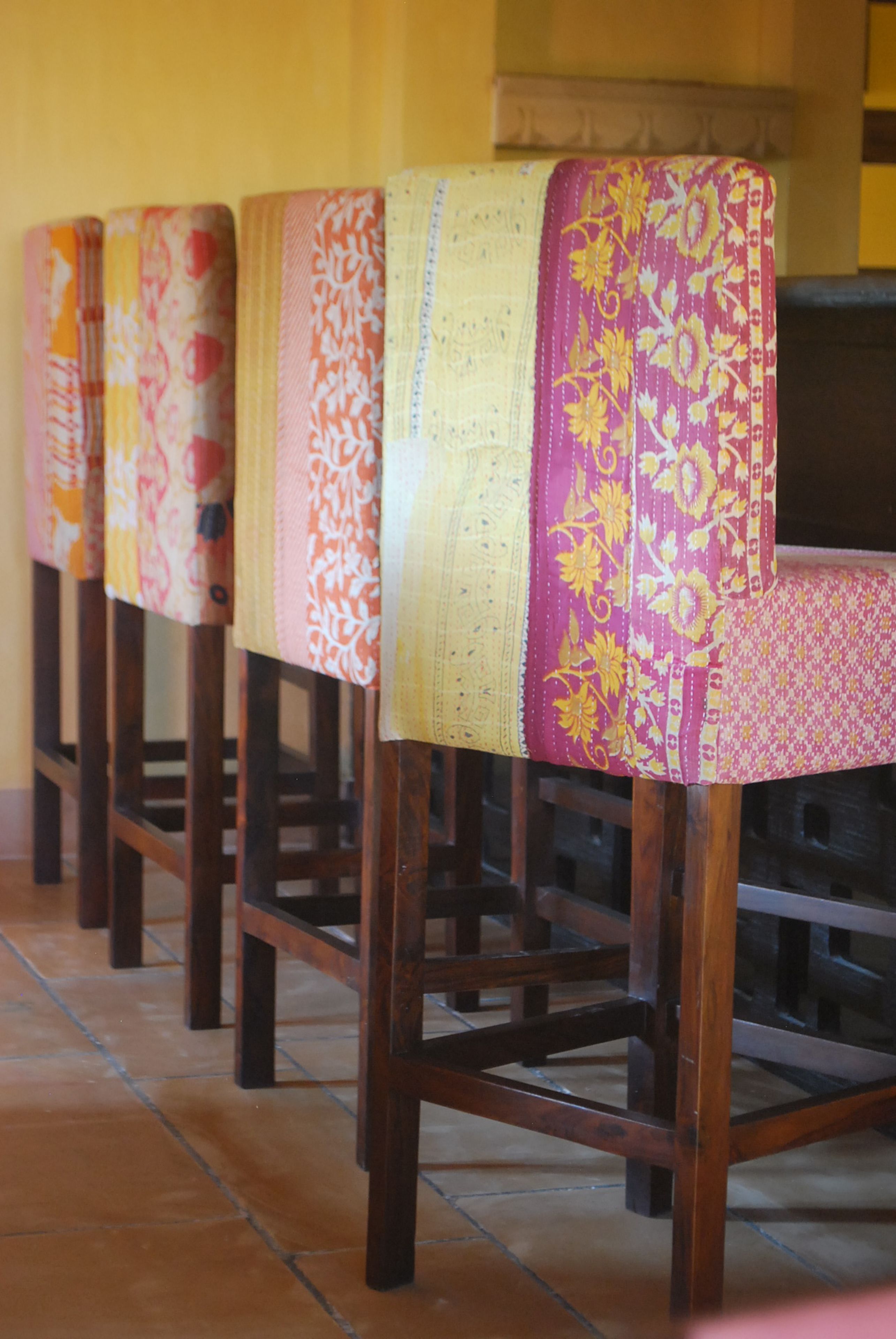 A row of wooden chairs with colorful fabric covers.