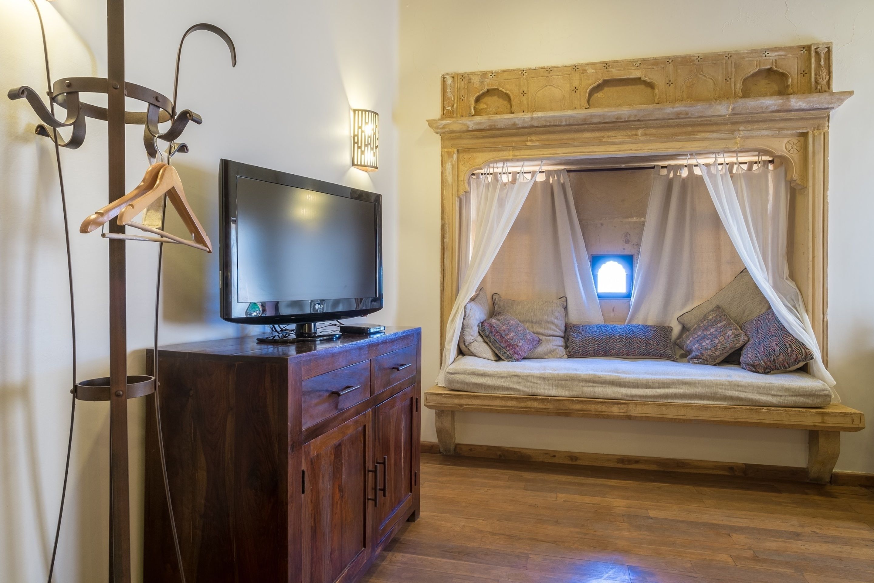 A cozy room with a wooden bench bed, a TV on a wooden cabinet, and a wall-mounted coat rack.