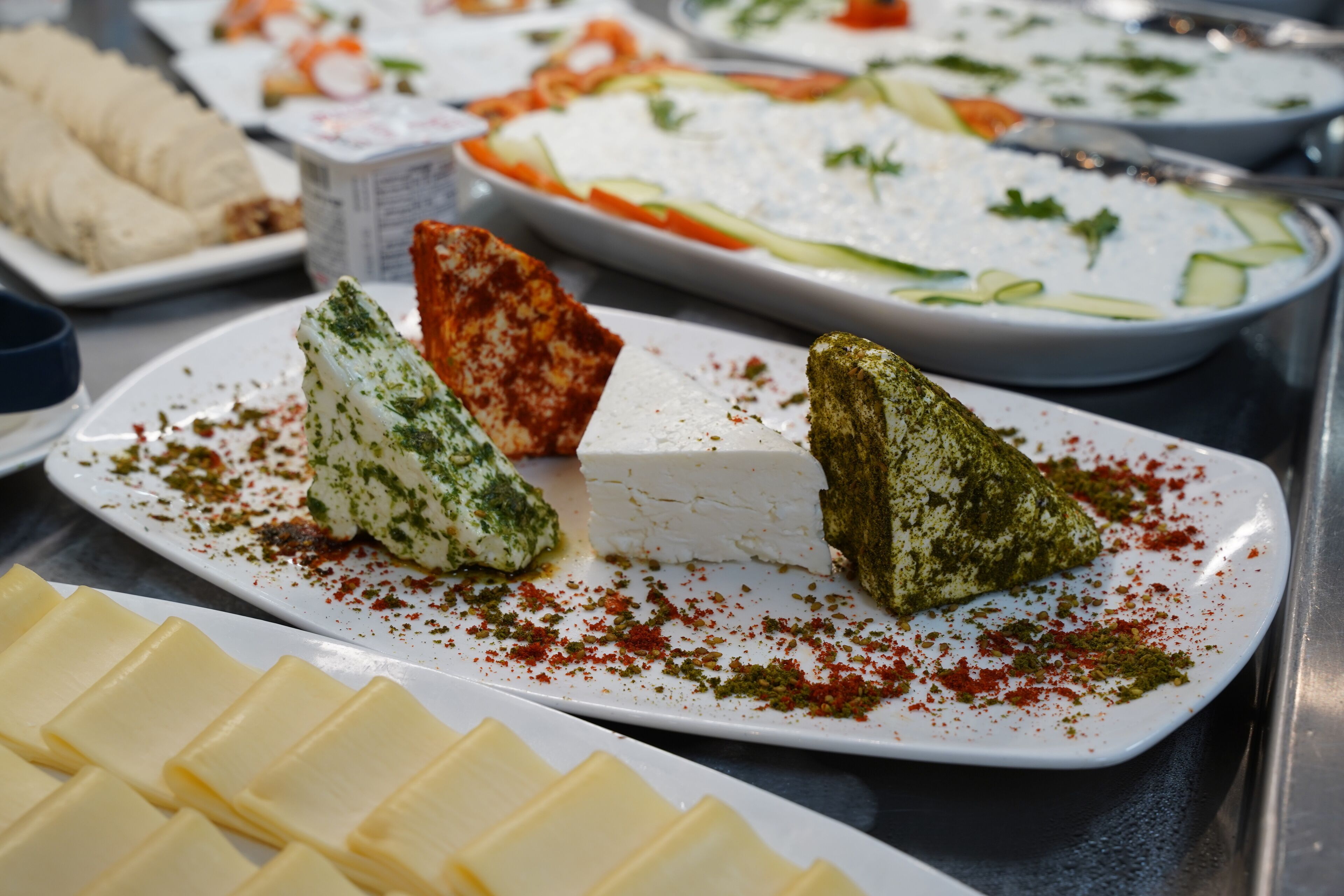 A buffet with various dishes including cheese, vegetables, and a white creamy dish.