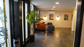 A modern interior with a potted plant, two chairs, a trash bin, and a wall-mounted air conditioner. - Spirit of Herzl Hotel (Jerusalem)