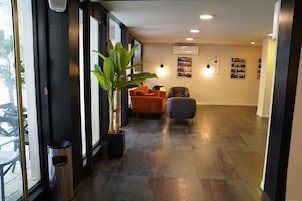 Un interior moderno con una planta en maceta, dos sillas, un cubo de basura y un aire acondicionado de pared.