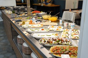 Un bufé con diversos platos, entre ellos ensaladas, frutas y quesos.