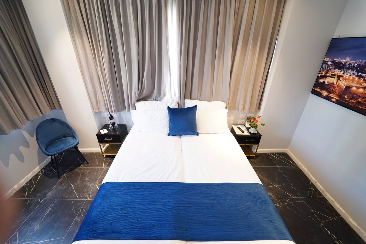 Une chambre d’hôtel avec un grand lit, une chaise, une table de chevet et un tableau au mur.