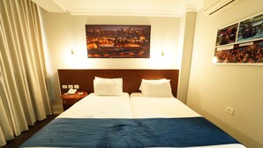 A hotel room with two beds, a cityscape view, a nightstand with a phone, and a wall-mounted picture. - Spirit of Herzl Hotel (Jerusalem)