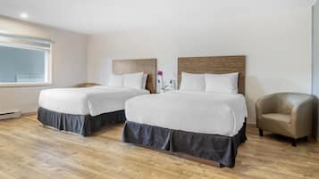 A hotel room with two beds, a chair, and a window.