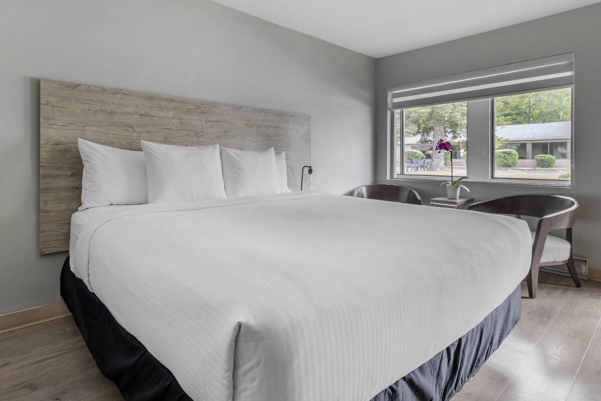 A large bed with a wooden headboard, a bedside table, and a chair.