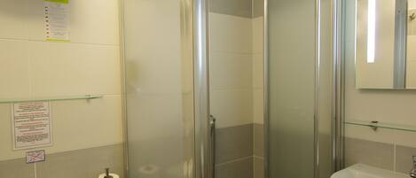 Un baño con inodoro, ducha envuelta en vidrio y lavamanos.