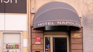 L’entrée d’un hôtel, avec une enseigne indiquant « HÔTEL NAPOLÉON » et un comptoir d’accueil.