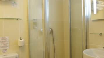 A bathroom with a glass-enclosed shower, a toilet, and a sink.
