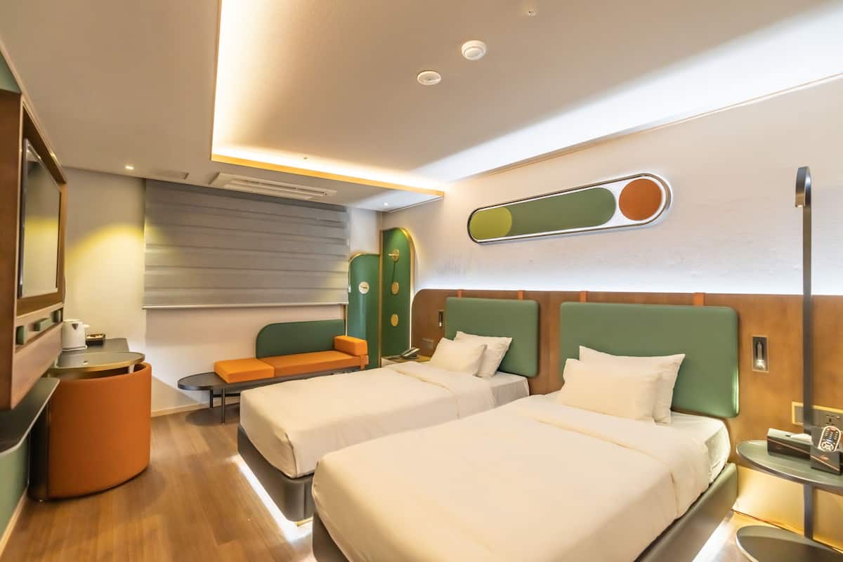 Une chambre d’hôtel avec deux lits, un coin salon et une petite table.