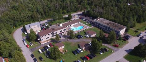 Vista aérea de una zona residencial con varios edificios, una piscina y un estacionamiento.