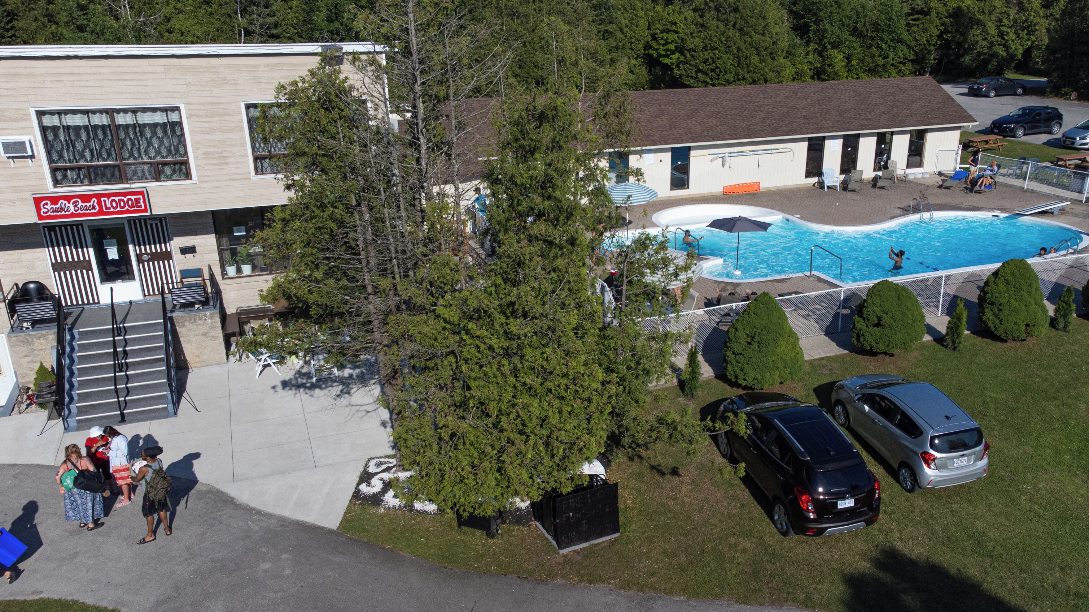 Una cabaña con piscina, mobiliario exterior y zona de estacionamiento.