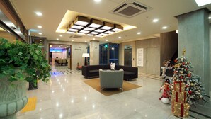 A modern lobby with a reception desk, seating area, and a Christmas tree. - Poong Gyung Hotel (Seogwipo)
