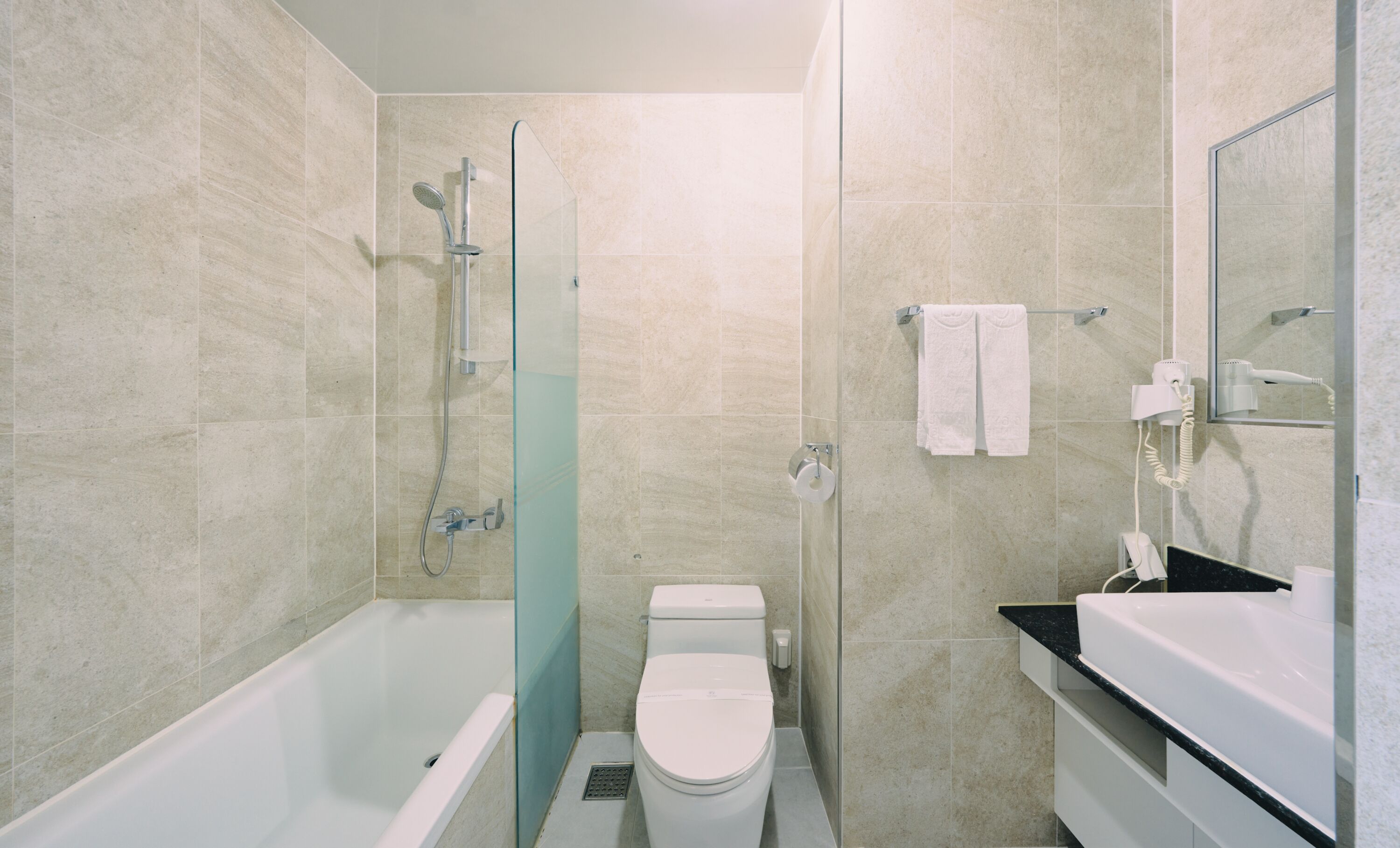 Une salle de bain moderne avec une douche à parois de verre, des toilettes blanches et un meuble-lavabo avec un miroir.