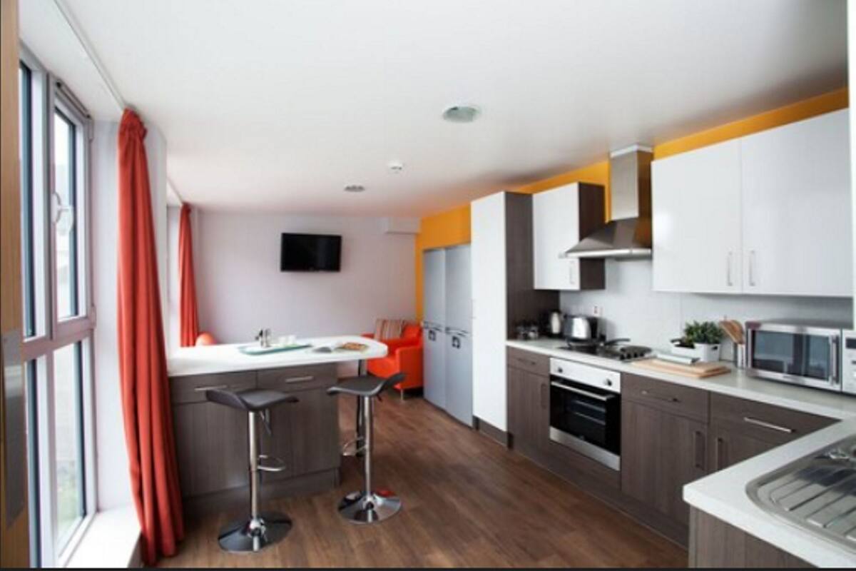 A modern kitchen with a central island, bar stools, and a built-in oven.
