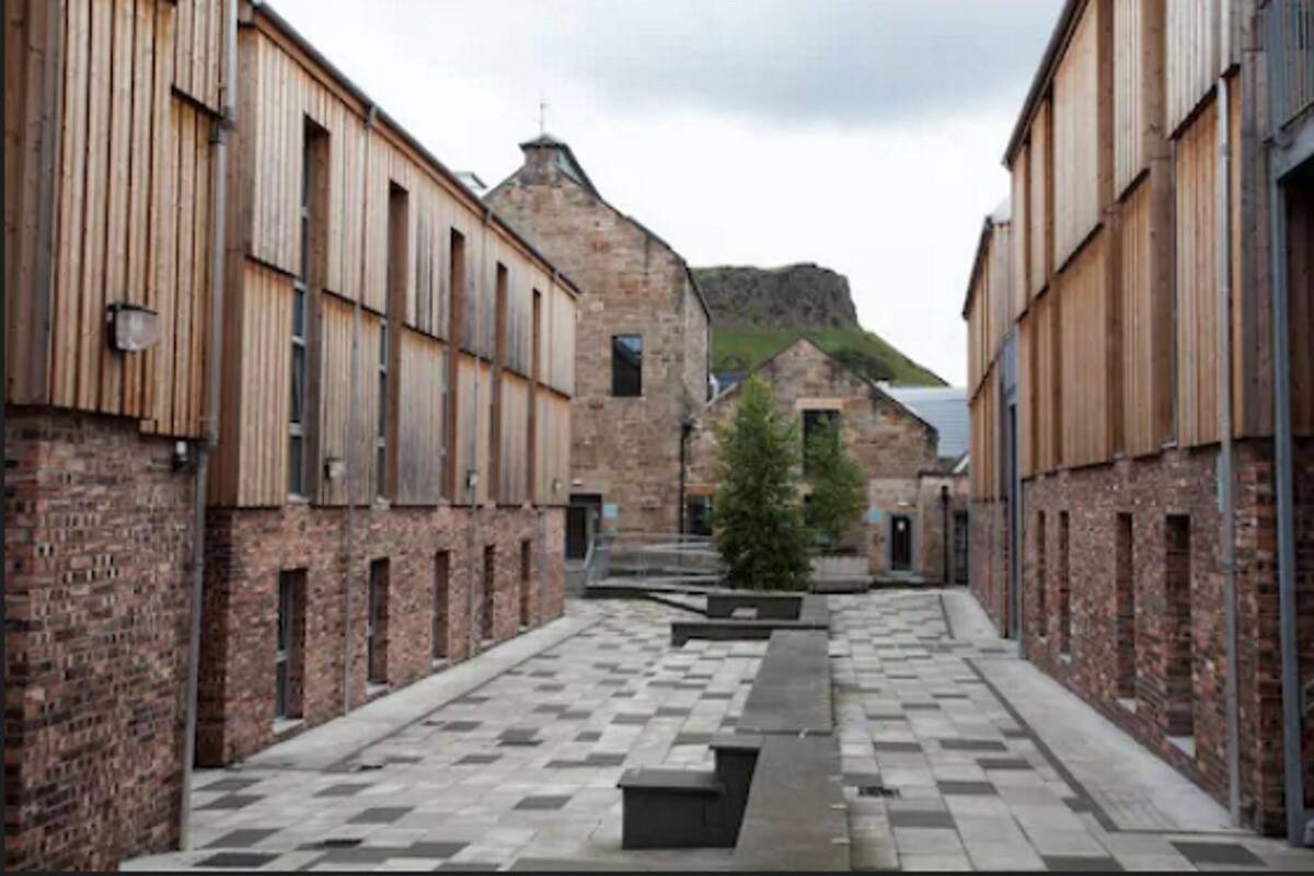 A narrow street with brick buildings, a central pathway, and a small tree.
