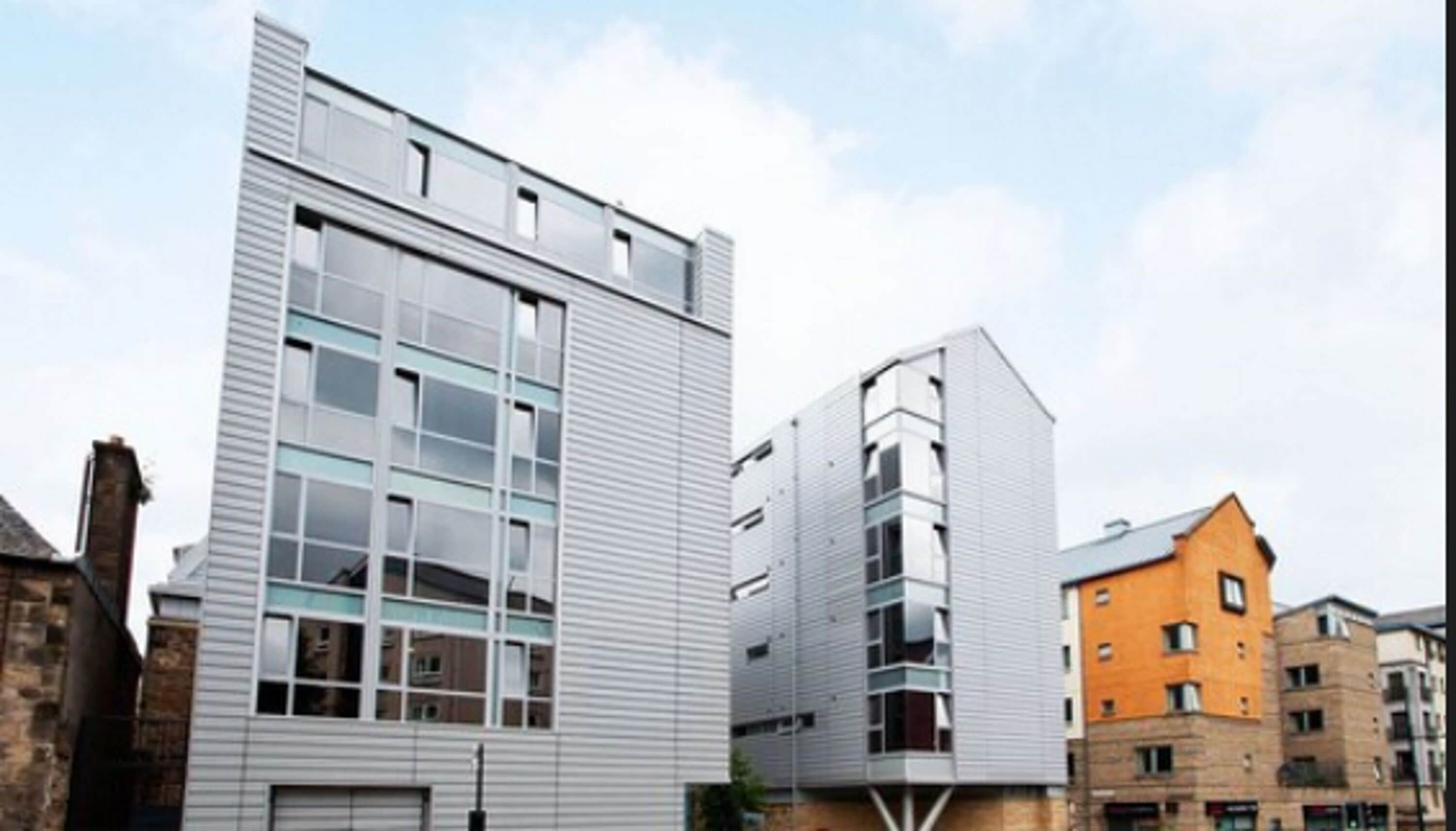 A modern building with a flat facade, large windows, and a mix of residential and commercial spaces.