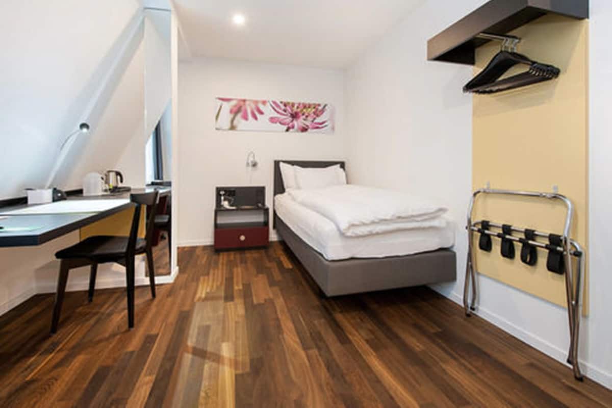 Una camera compatta con un letto, una scrivania e una sedia.