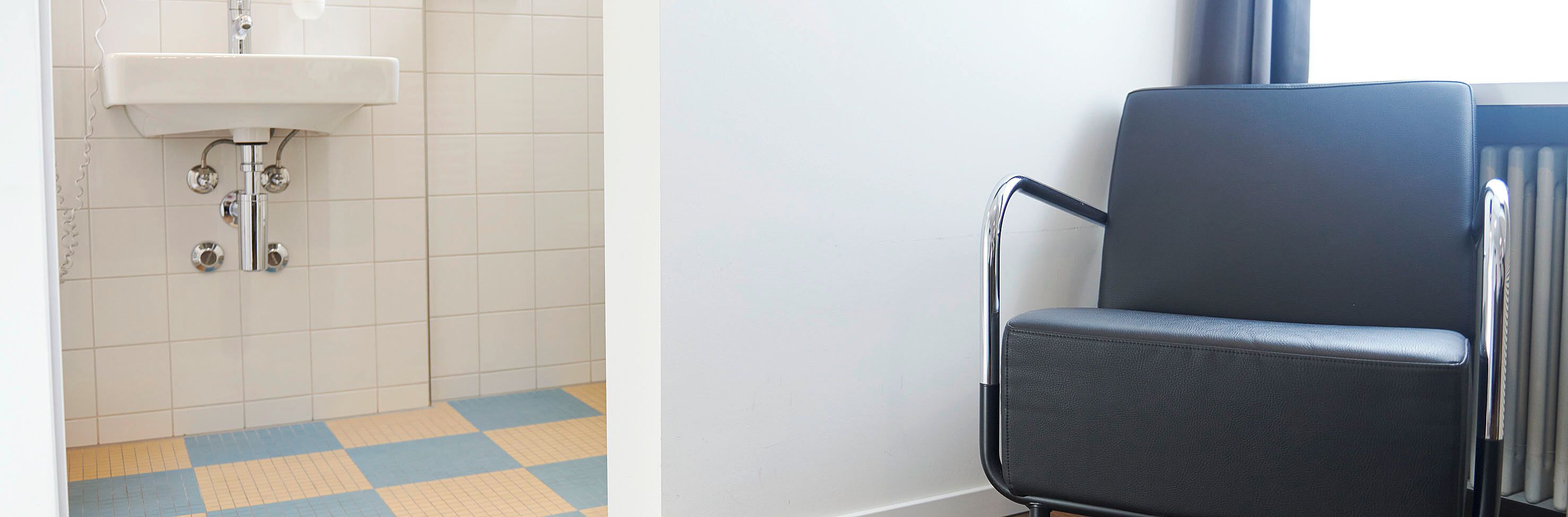 A bathroom with a white sink, chrome fixtures, and a checkered floor.
