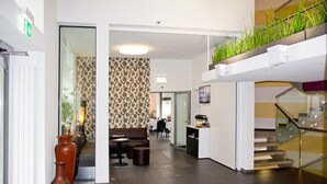 Un moderno vestíbulo de hotel con una zona de estar, una escalera y vistas al comedor.
