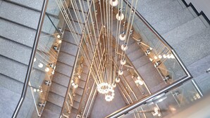 Una escalera moderna con barandillas de vidrio y una lámpara con diseño geométrico.