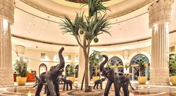 A lobby with a palm tree and three elephant statues.