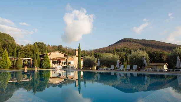 A pool with clear reflections, a stone building, and a mountainous backdrop. - Residenza di Rocca Romana (Sutri)