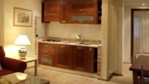 A spacious living area with a high ceiling and a kitchen area with wooden cabinets. - Residenza di Rocca Romana (Sutri)