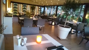 An outdoor dining area with tables and chairs, potted plants, and a large planter with a tree. - Hotel Gallus (Zagreb)