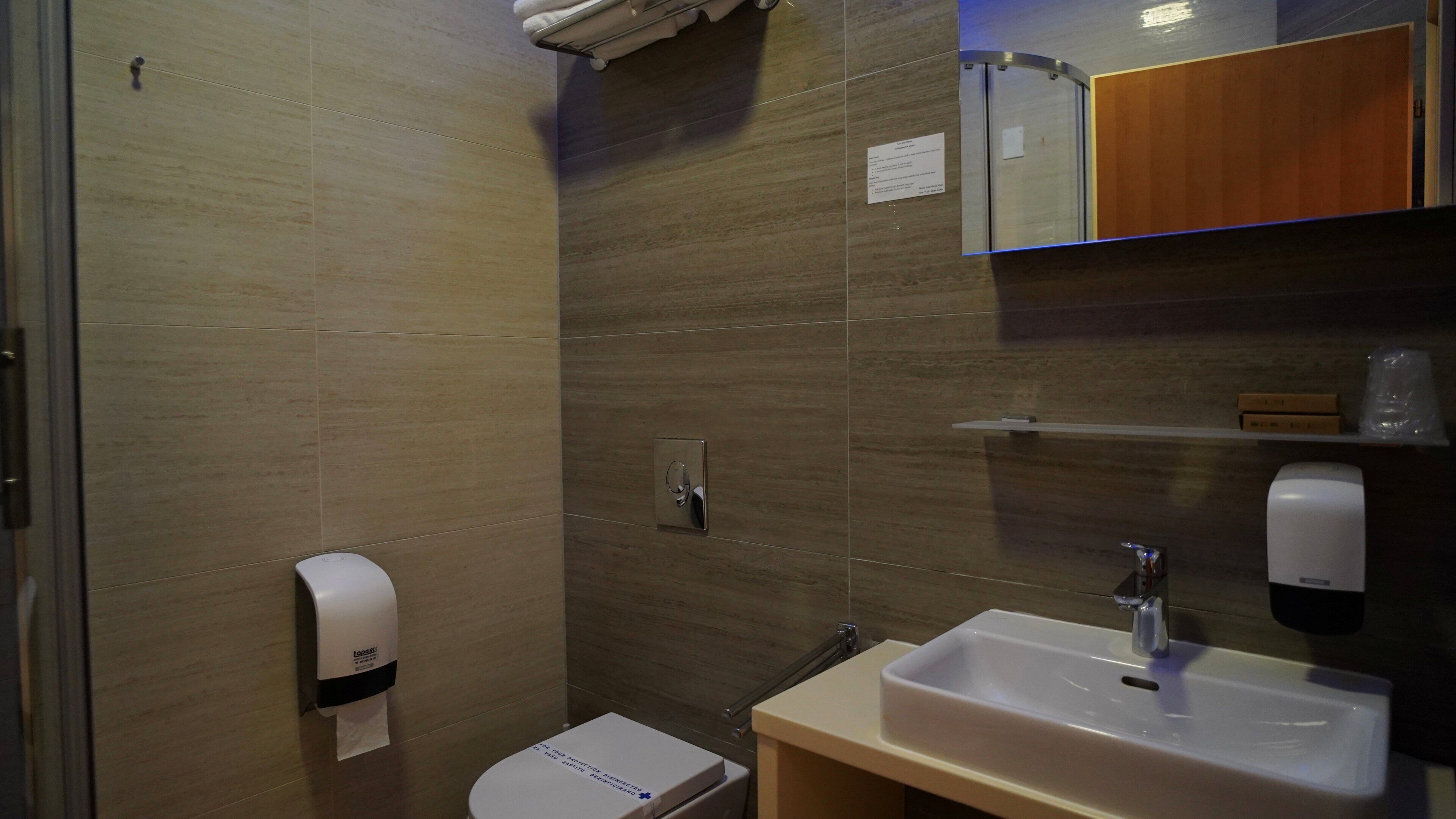 A small, modern bathroom with a toilet, a sink, and a mirror.