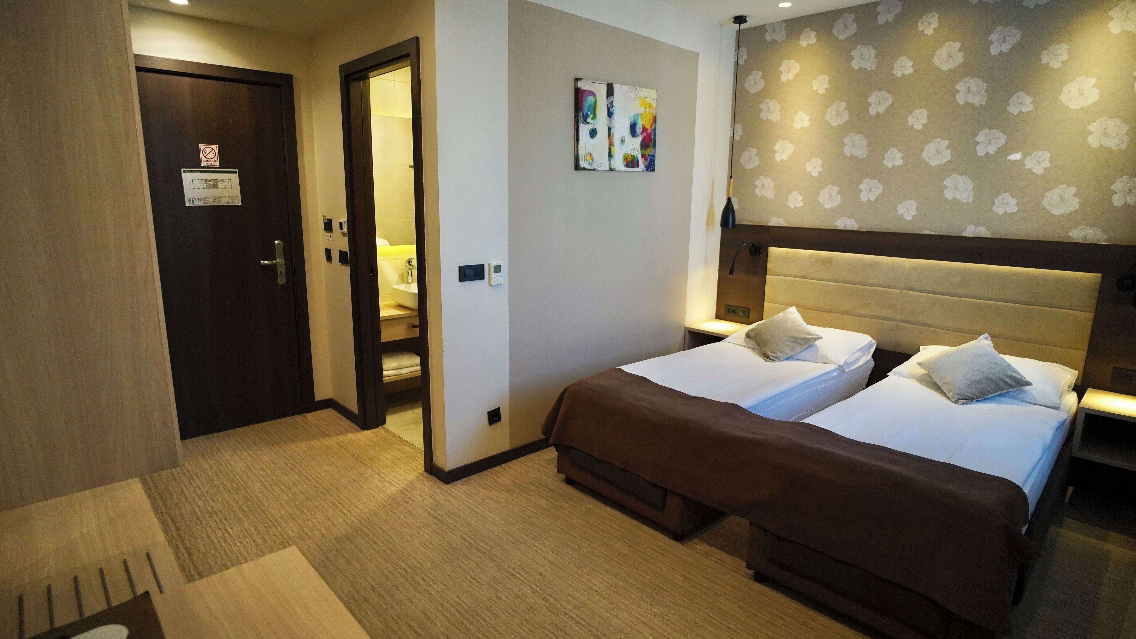 Hotelkamer met twee bedden, een badkamer met douche en een deur met een rookvrij bordje.