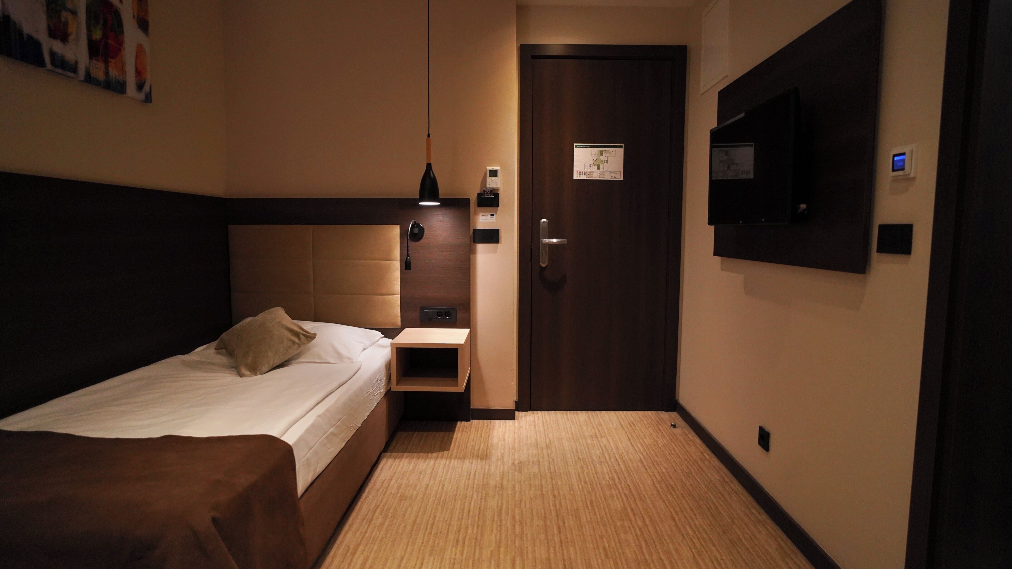 Habitación de hotel con cama, mesita de noche, lámpara y una puerta con un mapa.